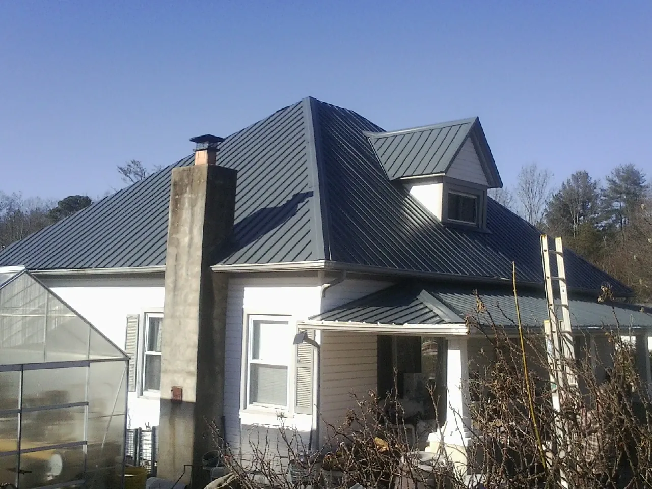 Dark blue standing seam metal roof on a white farmhouse with dormer — Slate & Tile Roof Repair by Roofing Brothers in Karns City