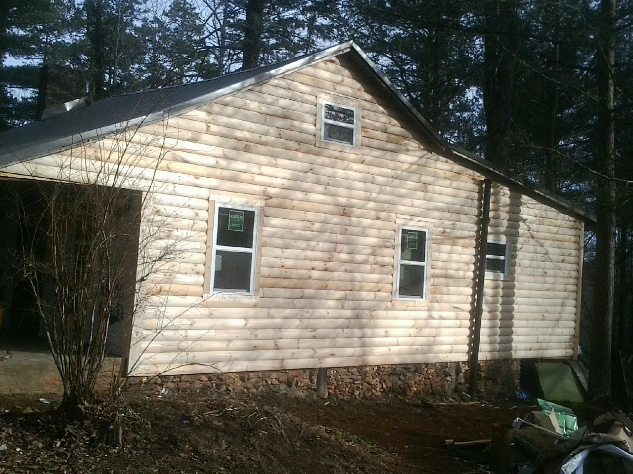 New log siding and dark metal roofing on a gable end in Karns City