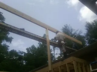 Carpenter setting a ridge beam over a new addition frame — Ice Dam Removal by Roofing Brothers in Karns City
