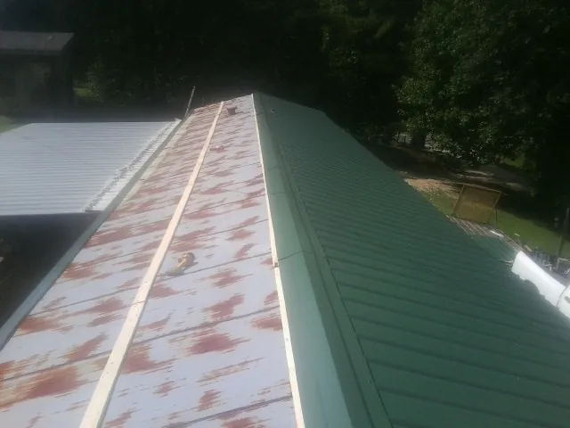 Old rusted panels beside newly installed green metal roofing — Wind Damage Roof Repair by Roofing Brothers in Karns City