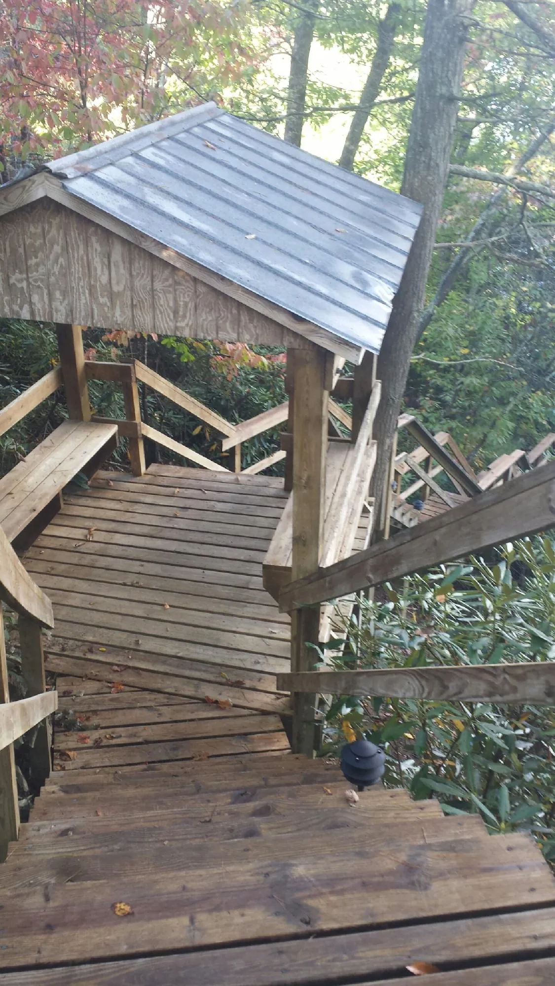 Metal roofed shelter over wooden steps on a wooded walkway — Skylight Repair & Installation work by our crew in Karns City