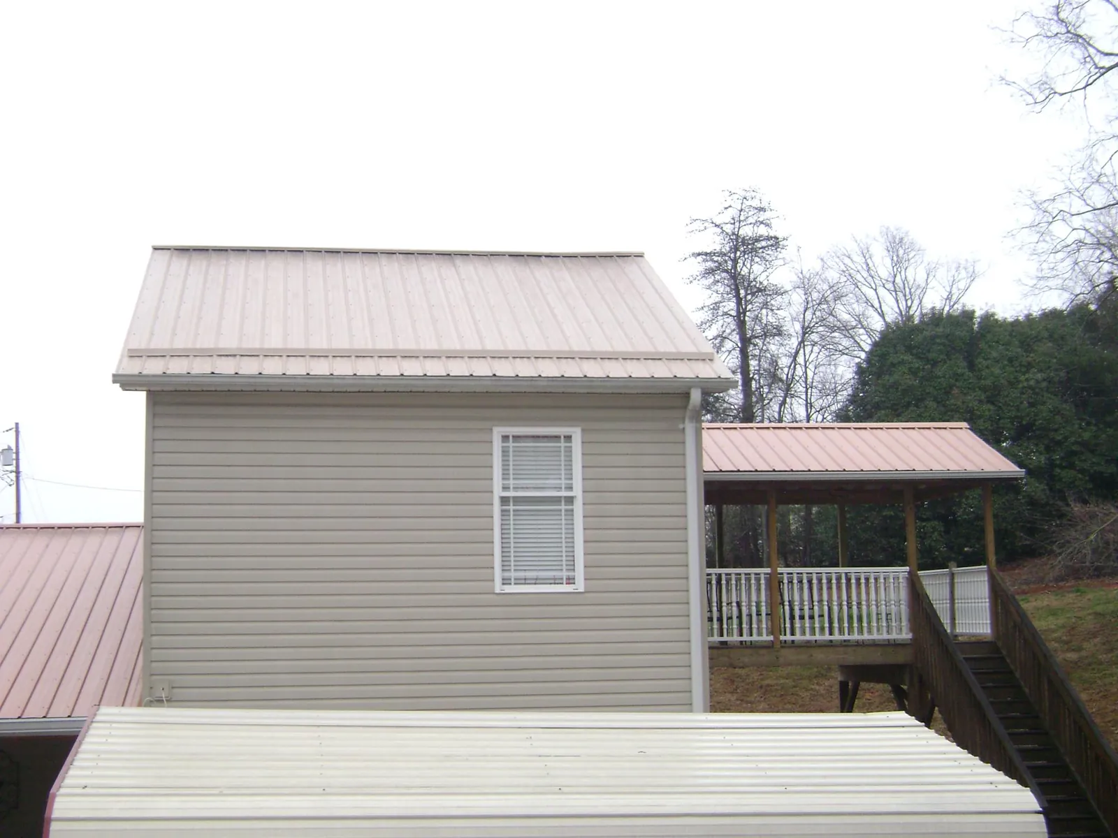 Tan metal roofs on a two story addition and attached porch, from a Roof Replacement job in Karns City