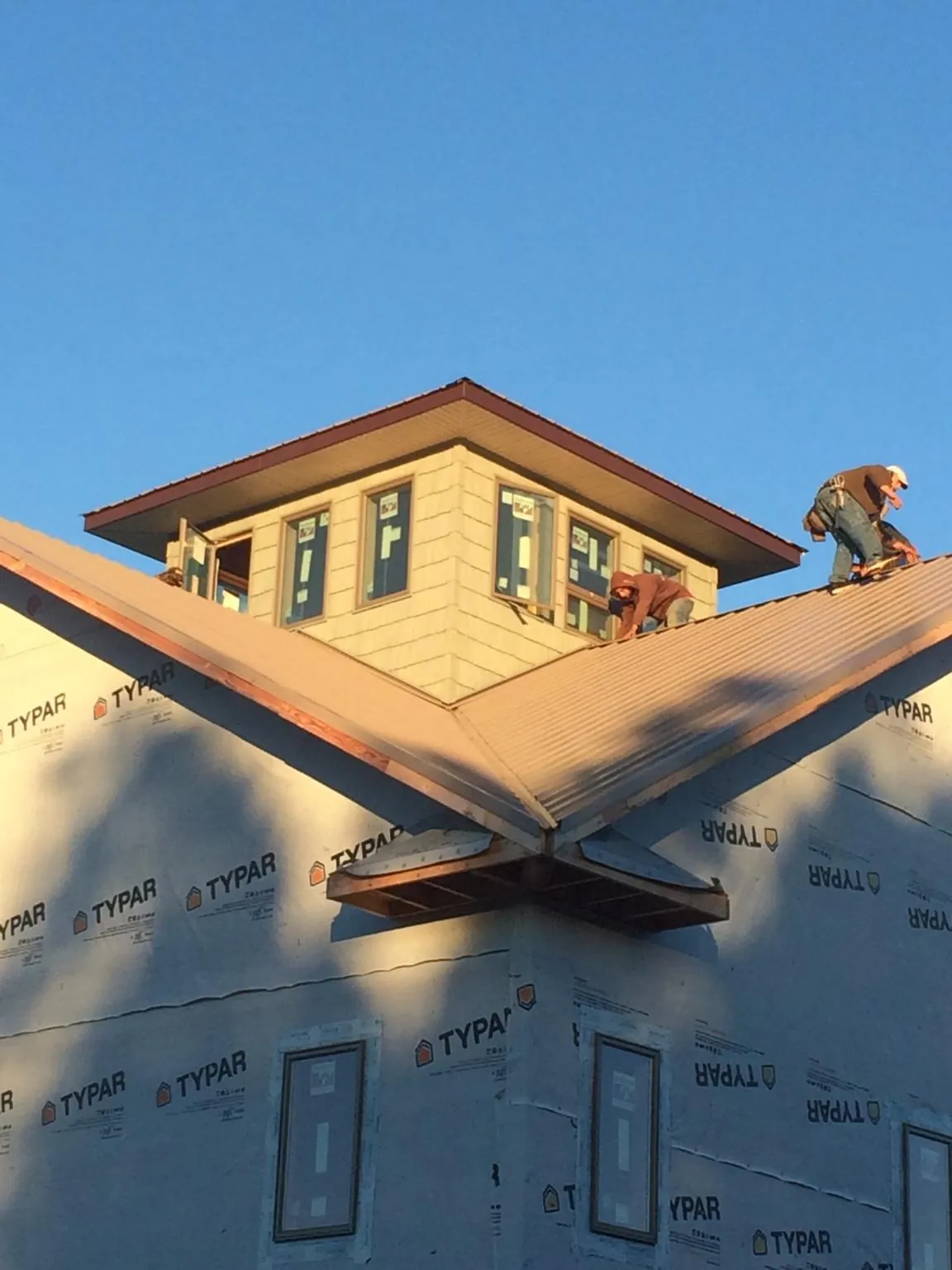 Roofers working around a rooftop cupola on a new metal roof at sunset — Roof Waterproofing in Karns City by Roofing Brothers